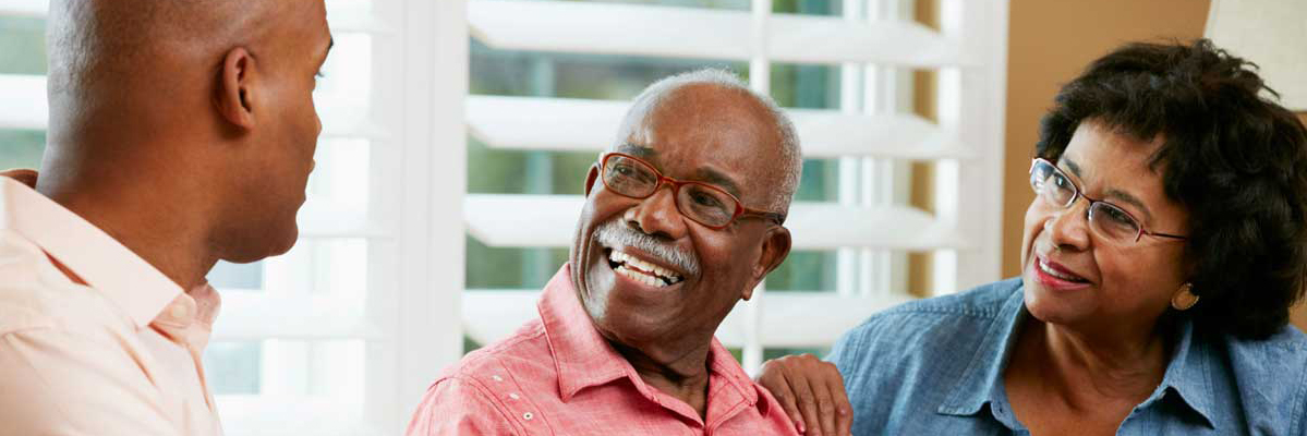 A young man speaking to an older couple, all sitting